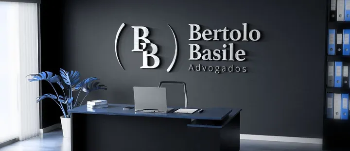 Logotipo de Bertolo Basile Advogados, com o monograma BB entre parênteses, em letras prateadas na parede escura de um escritório